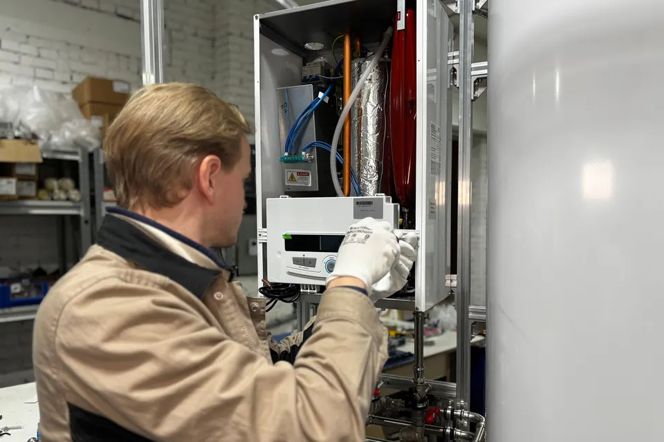 Monteur werkt aan de voorkant van een cv-ketel naast een warmwatervat